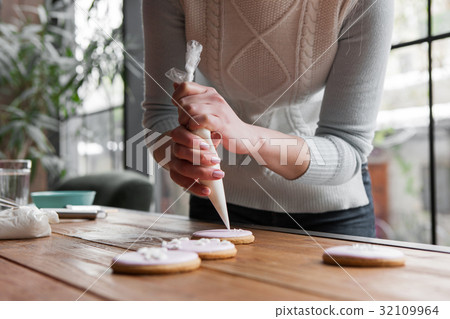 Female chef decorating gingerbread with pastry bag Female chef decorating gingerbread with pastry bag 32109964