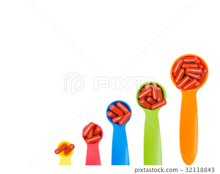 red capsules pills on colorful measuring spoon. 32118843