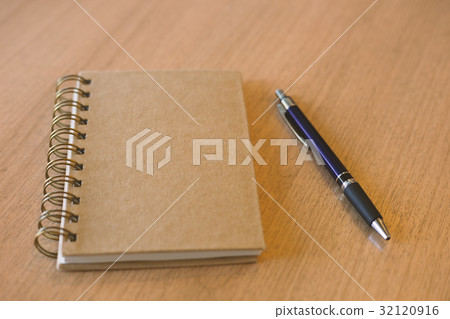 Brown notebook with pen on wooden desk 32120916