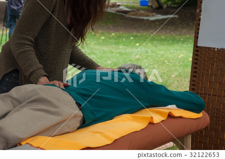 Woman massaging a man in a public garden Woman massaging a man in a public garden 32122653