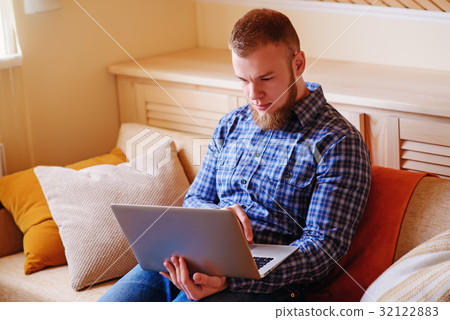 Young man working absorbed on laptop at home Young man working absorbed on laptop at home 32122883