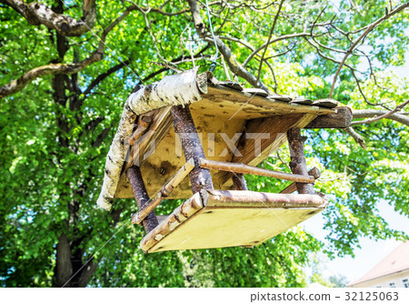 Wooden bird house hanging on the green tree 32125063
