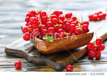 Red currant with drops of water in a wooden bowl. Red currant with drops of water in a wooden bowl. 32125083