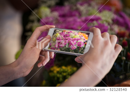 Woman's hand taking photograph of flower bouquet 32128540