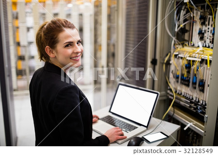 Technician using laptop while analyzing server Technician using laptop while analyzing server 32128549