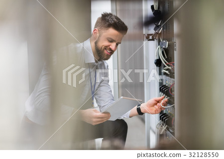 Technician using digital tablet while analyzing server Technician using digital tablet while analyzing server 32128550
