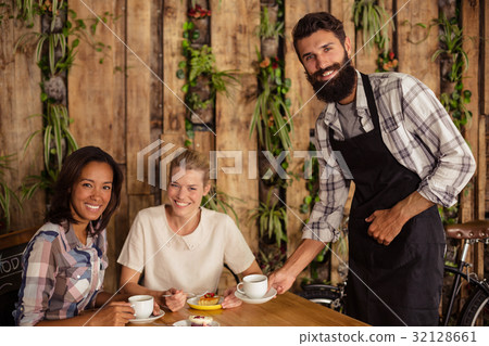 Waiter serving a cup of coffee to customer 32128661