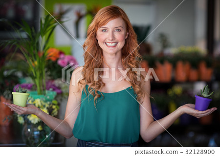Female florist holding plant pot at flower shop 32128900