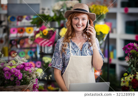 Female florist talking on mobile phone while using laptop 32128959