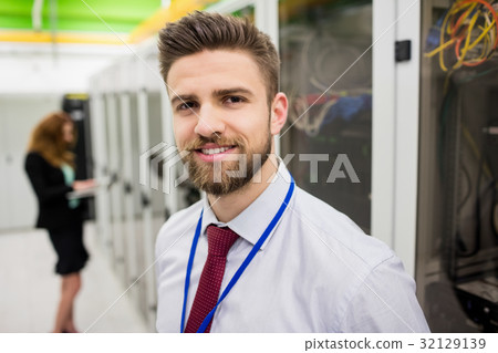 Smiling technician standing in a server room Smiling technician standing in a server room 32129139