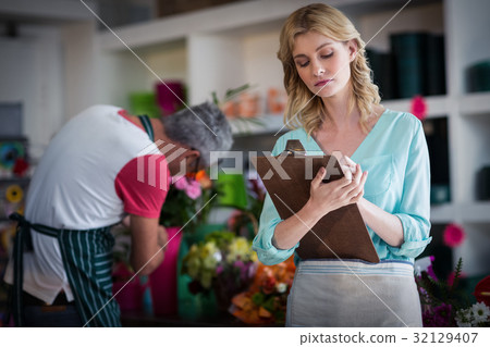 Female florist noting on clipboard 32129407