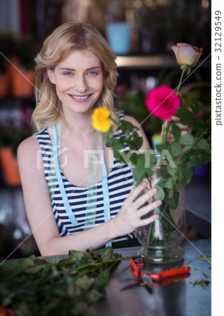 Smiling female florist arranging flower bouquet in vase at flower shop 32129549