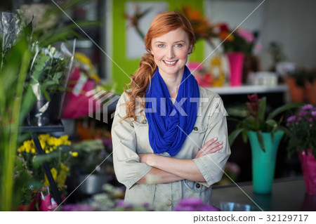 Happy female florist standing with arms crossed in flower shop Happy female florist standing with arms crossed in flower shop 32129717