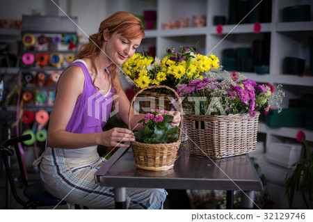 Female florist preparing basket of flowers Female florist preparing basket of flowers 32129746