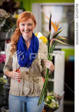 Smiling female florist trimming flower stem 32129748