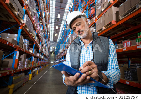 Warehouse worker wearing writing on clipboard 32129757
