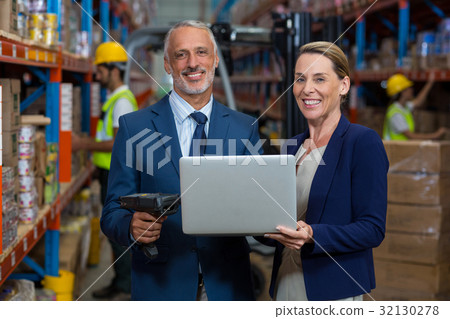Warehouse manager and client using laptop 32130278