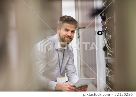 Technician using digital tablet while analyzing server Technician using digital tablet while analyzing server 32130286