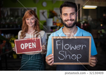Man holding slate with flower shop sign and woman holding open signboard Man holding slate with flower shop sign and woman holding open signboard 32130409