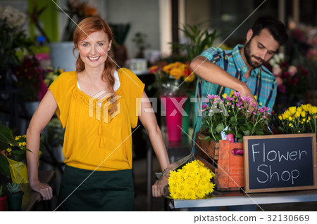 Female florist standing while male florist arranging flower bouquet 32130669