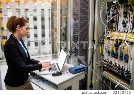 Technician using laptop while analyzing server Technician using laptop while analyzing server 32130756