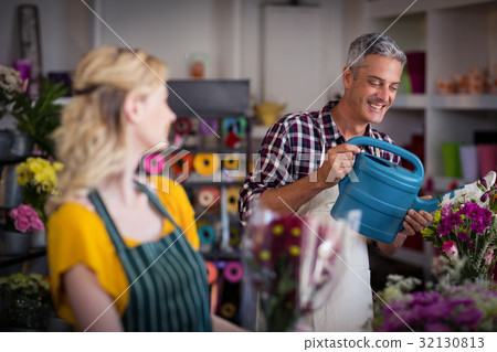 Smiling florist watering flowers 32130813
