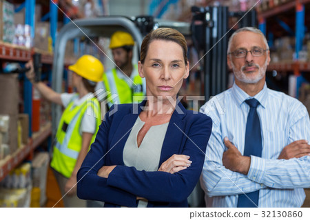 Portrait of warehouse manager and client standing with arms crossed Portrait of warehouse manager and client standing with arms crossed 32130860