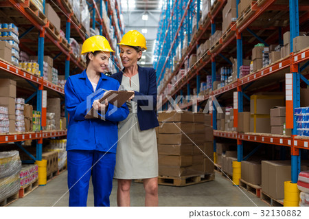Warehouse manager and worker discussing with clipboard 32130882