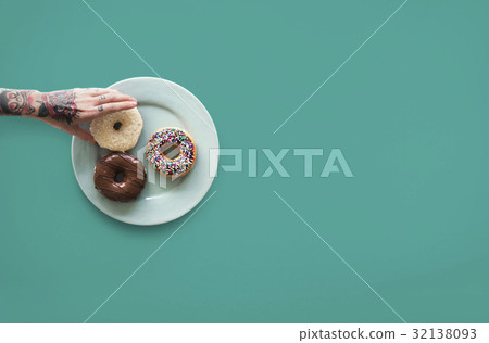 Hand with tattoo reaching for donut Hand with tattoo reaching for donut 32138093