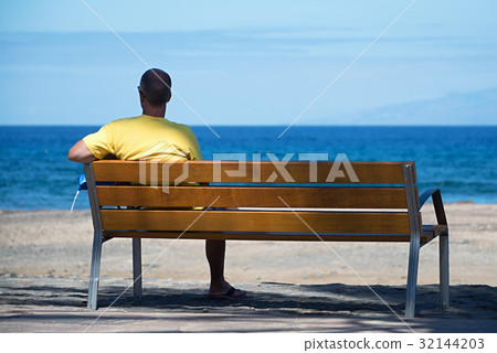 Men sitting alone on the bench in front of the sea Men sitting alone on the bench in front of the sea 32144203