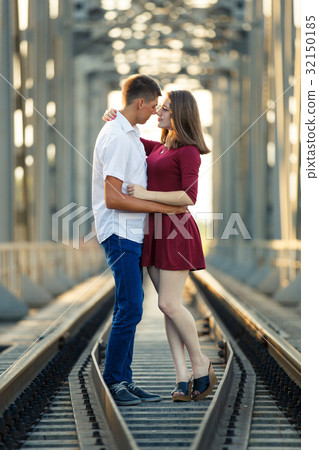 Young man and a girl kissing on railway bridge 32150185