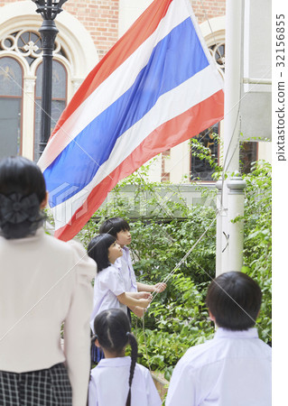 A teacher and students are standing and looking at two students pulling national flag A teacher and students are standing and looking at two students pulling national flag 32156855