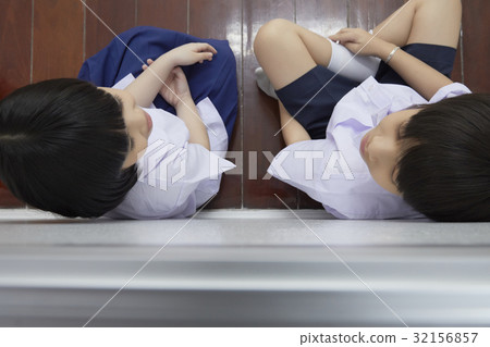 A picture of two pupils sitting and looking at each other on floor. 32156857