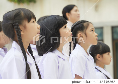 schoolchildren are standing, queuing and looking at above. 32156862