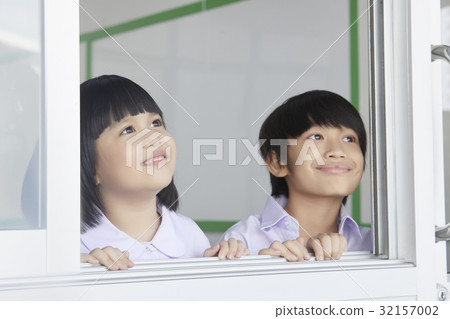 Children are smiling and looking at something outside the class. 32157002
