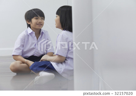 Two students are sitting and talking together beside the wall Two students are sitting and talking together beside the wall 32157020