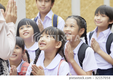 The pupils are smiling and clasping the hands to greet their teacher. 32157058