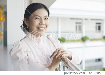 The teacher is standing and smiling near the balcony 32157059
