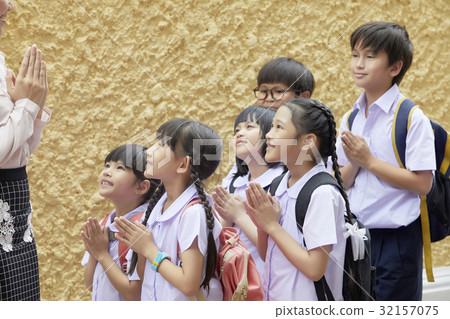 The primary pupils are looking at their teacher, greeting and smiling. 32157075