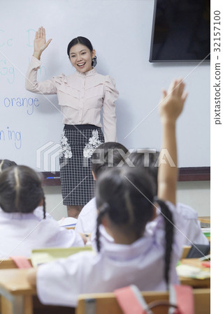 a teacher is encouraging her pupils to raiser hand, answer her question. a teacher is encouraging her pupils to raiser hand, answer her question. 32157100