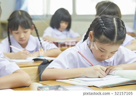 a photo of schoolchildren sitting and writing in a class. 32157105