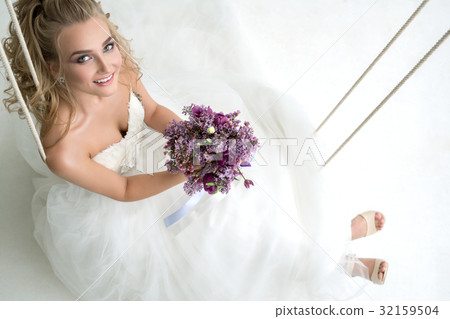Young bride in studio on swing with fine bouquet Young bride in studio on swing with fine bouquet 32159504