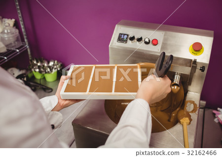 Worker filling mould with melted chocolate 32162466