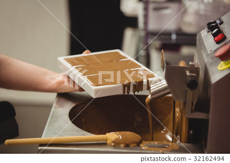 Worker filling mould with melted chocolate 32162494