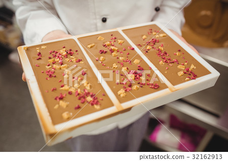 Mid section of worker holding chocolate mould 32162913