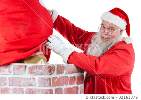 Santa claus placing gift box into a chimney Santa claus placing gift box into a chimney 32163379