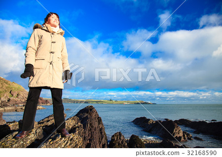 Woman standing on rock cliff at ocean. 32168590