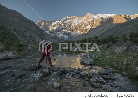 Tourist crossing stream 32170253