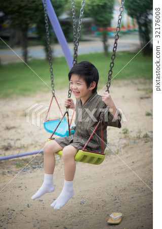 Asian child in kimono playing on swing i 32176008
