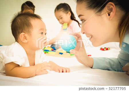 Mom is playing toys with her baby in the bedroom. 32177705